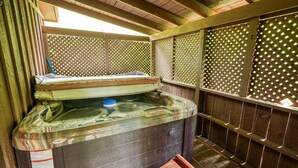 Een hottub met een houten bank en een houten omheining met een lattenstructuur.