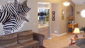 A living room with a zebra wall art, a sofa, a coffee table, and a lamp.