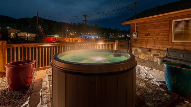 Un jacuzzi en una cabaña de madera con una pared de piedra y una terraza de madera.