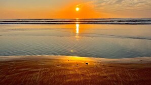 A beach at sunset with calm waters reflecting the sky.
