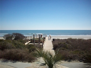 A wooden boardwalk leading to a beach with a clear view of the ocean.