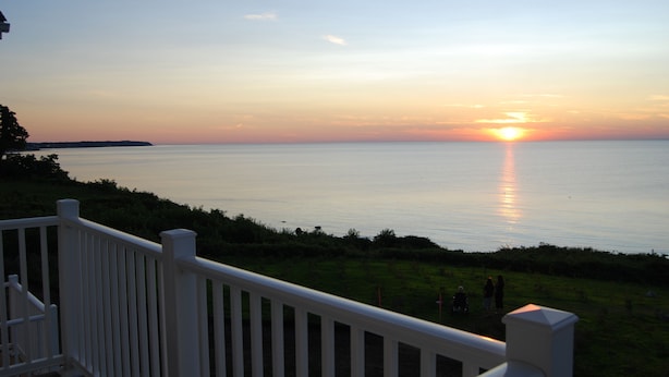 Vista del atardecer desde un balcón con vista al mar tranquilo.