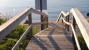 Una pasarela de madera que lleva a una playa con un cartel en blanco al final.