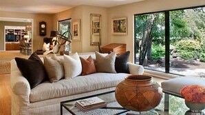 A modern living room with a sofa, coffee table, and a large window with a view of greenery.