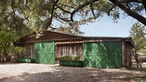 A rustic barn with two green doors and a wooden exterior.