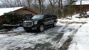 A black GMC Yukon XL SUV parked on a snow-covered driveway with a wooden house in the background. - Million-Dollar Views, spectacular! Sugar Mountain Cabin 3 Bedrms 3 bath sleeps 7 (Sugar Mountain)