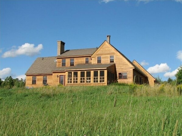 Rustic cabin surrounded by tall grass in a natural setting.