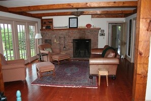 Cozy living room with a brick fireplace, leather sofa, and wooden beams.