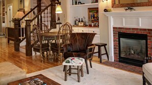 Una sala de estar acogedora con chimenea, muebles de madera y una escalera que lleva a otra habitación.