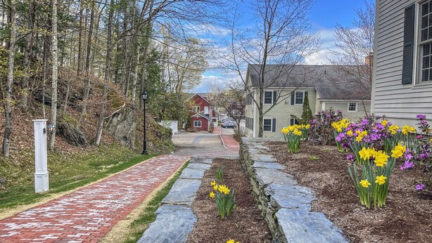 Un sendero pavimentado con bordes de piedra que conduce a una hilera de casas bajo un cielo despejado.