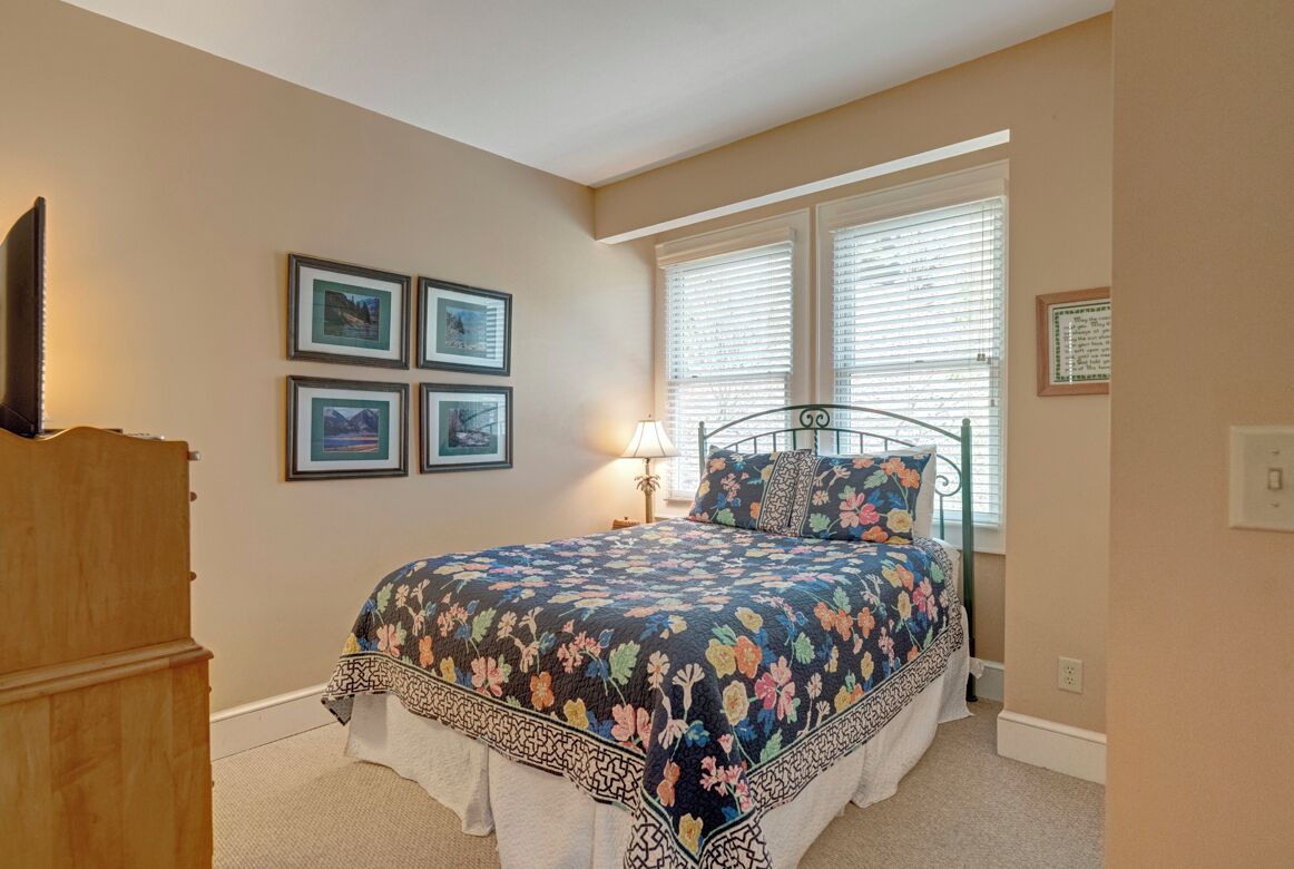 A bedroom with a bed, a dresser, and framed pictures on the wall.