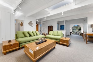 Uma sala de estar ampla com um sofá verde, mesa de centro de madeira e mesas laterais combinando.