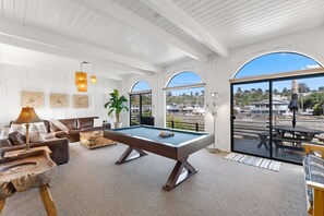 Un espace intérieur vaste et accueillant, doté d’une table de billard, de sièges confortables et de grandes fenêtres offrant une vue sur l’extérieur.