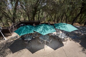 An outdoor patio with a stone table and chairs, surrounded by trees.