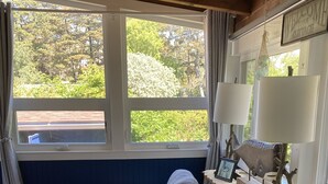 Una habitación acogedora con sofá, una mesita, una lámpara y vistas al exterior con vegetación.