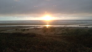 Vista de la playa con el sol poniéndose en el horizonte.
