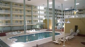 Una piscina interna con poltroncini prendisole e un balcone a più livelli.