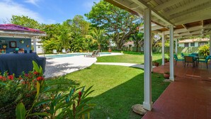 Un espacio exterior techado con piscina, sillas de descanso y zona de barbacoa.