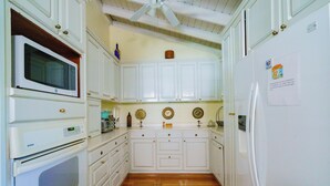 Una cocina con armarios blancos, microondas, horno y refrigerador.