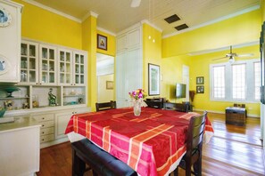 A dining area with a table set for four, a white cabinet with glass doors, and a yellow wall.