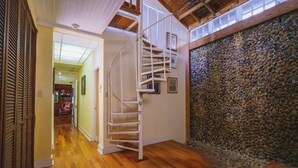 Una escalera de caracol en un pasillo con suelo de madera y pared de piedra.