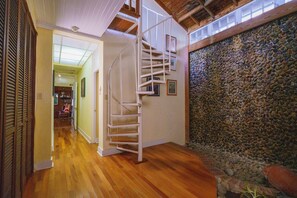 Stunning interior with a spiral staircase, polished wooden planks, and exposed wooden beams.