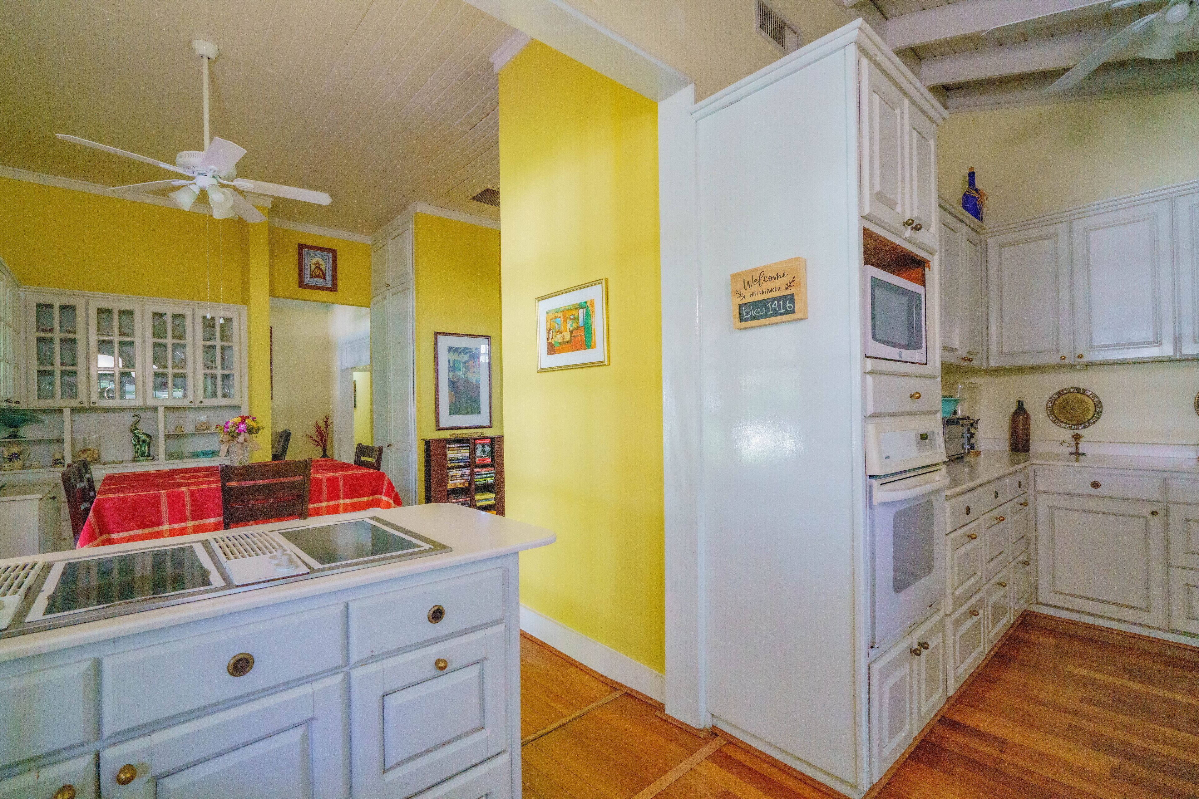 A kitchen with white cabinets, a microwave, and a ceiling fan.