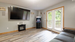 A living room with a flat-screen TV, a gaming console, and a sofa.