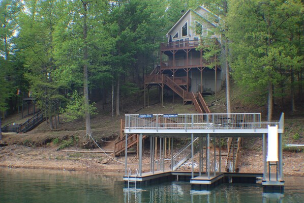 A wooden deck with a staircase leading to a house surrounded by trees. - Night Sky' Private Hot Tub Private Dock W/ Electric near Jump'n Bridge (LaFollette)