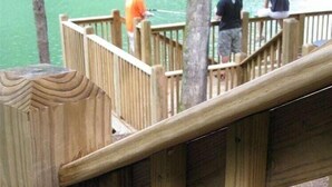 A wooden deck with railings overlooking a body of water.