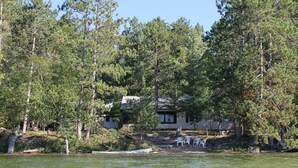A lakeside cabin with a dock, surrounded by dense forest.