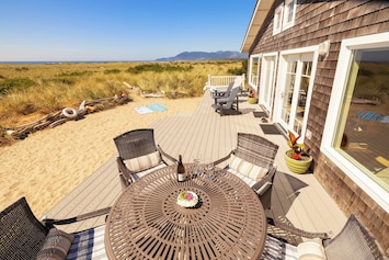 Large oceanfront deck with sandy play area, outdoor table & deck chairs