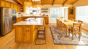 Una cocina amplia con armarios de madera, una isla grande y un comedor con mesa y sillas de madera.