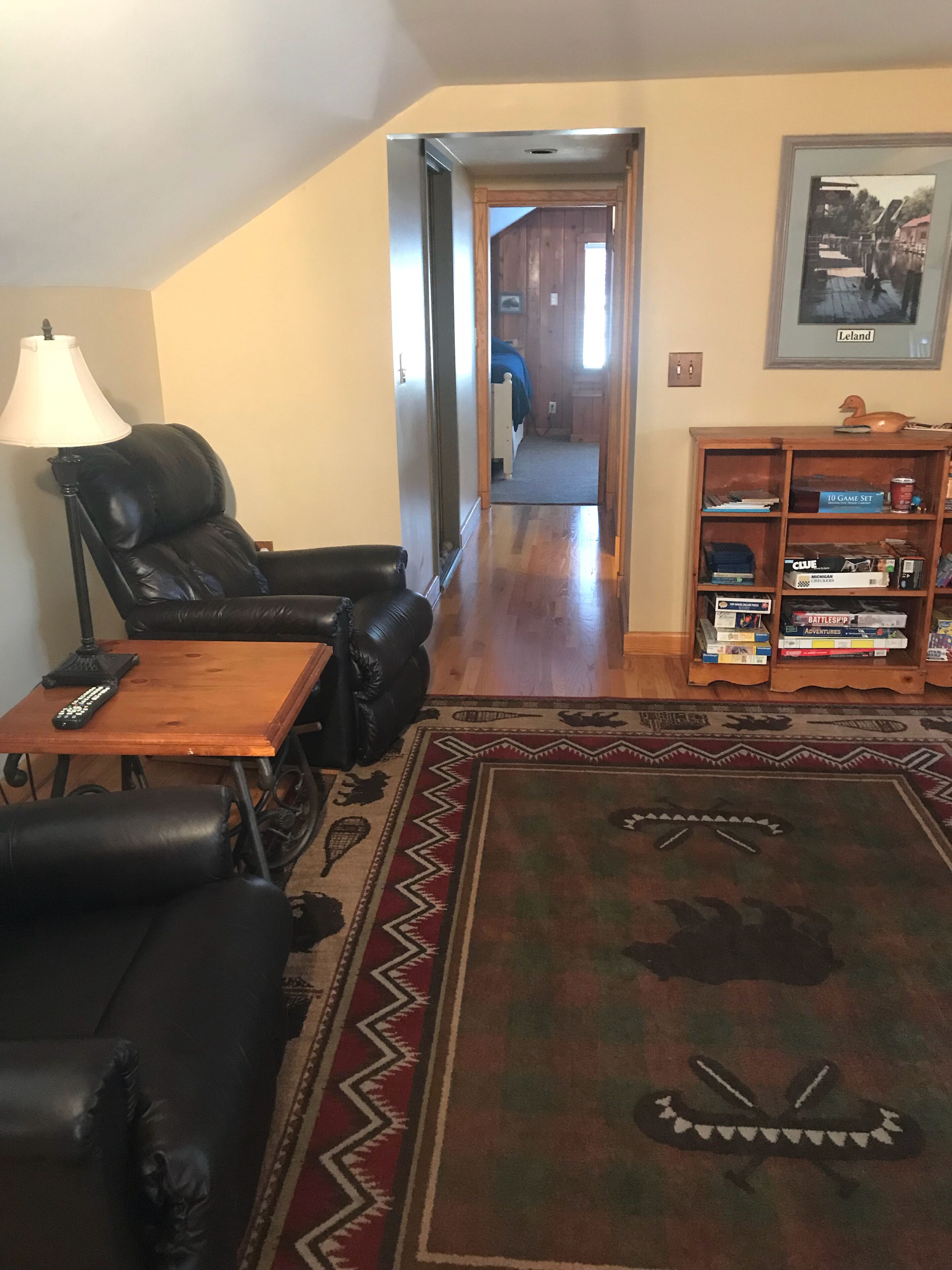 A living room with a leather sofa, a coffee table, a lamp, and a bookshelf.