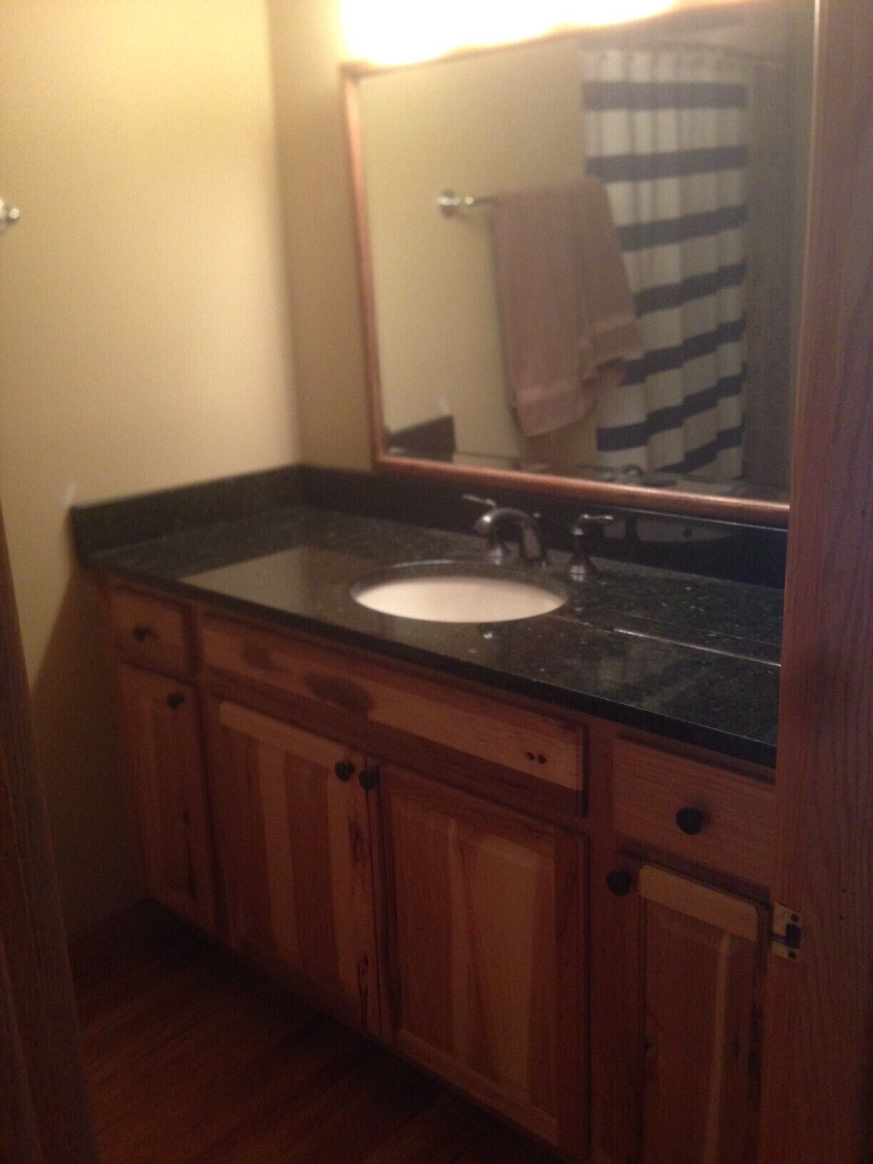 A bathroom with a wooden vanity, a sink, and a mirror.