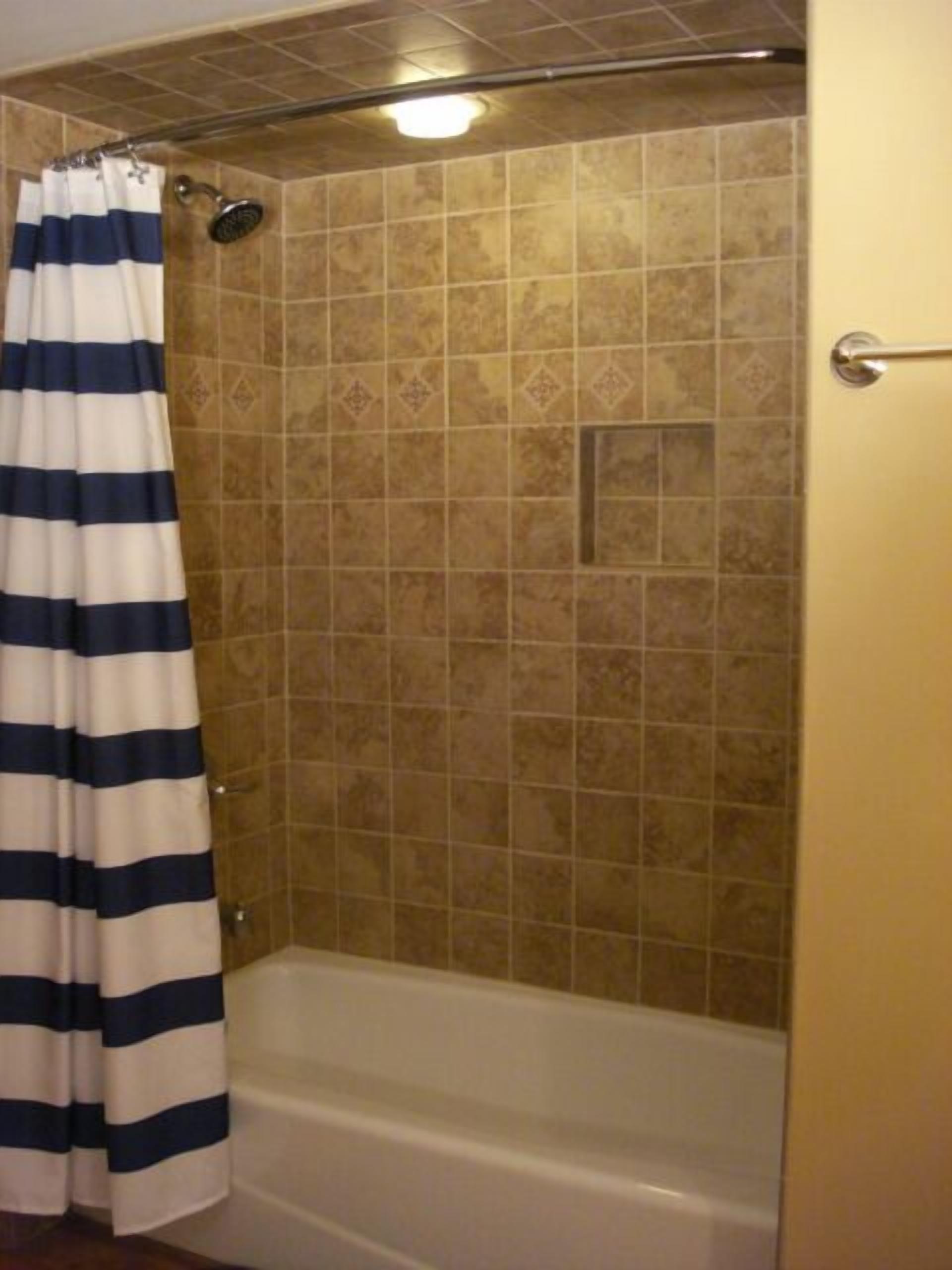 A bathroom with a bathtub, a shower, and a striped curtain.