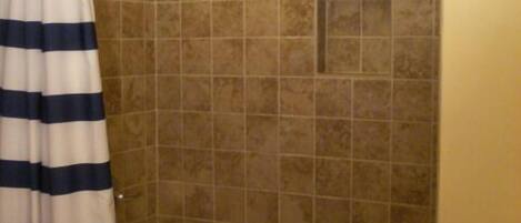 A bathroom with a bathtub, a shower, and a striped curtain.