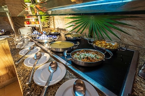 Enjoy a well-organized buffet with a variety of dishes and utensils.