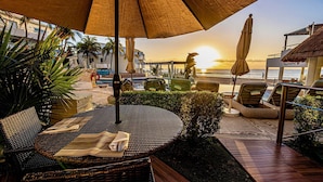 A beachside patio with wicker furniture, a table, and an umbrella. - Huge true Beachfront condo w/ full resort amenities & washer/dryer (Playa del Carmen)