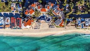 An aerial view of a resort with multiple buildings, a central pool, and a beach.