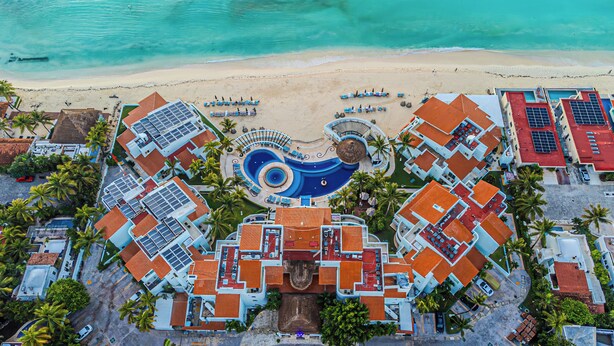 An aerial view of a resort with a central swimming pool, multiple guest rooms, and a beach. - Huge true Beachfront condo w/ full resort amenities & washer/dryer (Playa del Carmen)