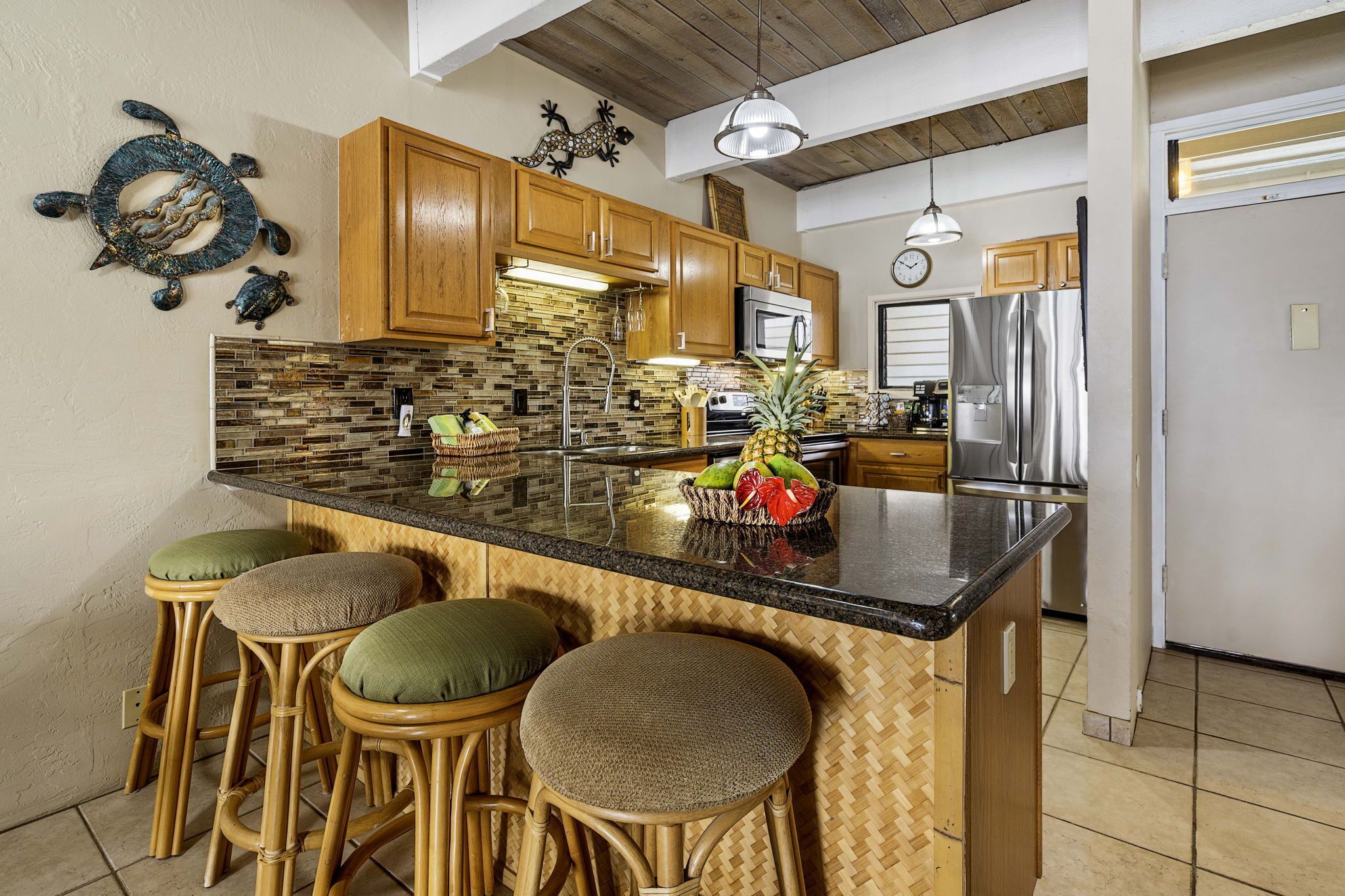 A kitchen with wooden cabinets, a black countertop, and a central island with stools.