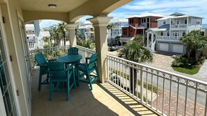 A balcony with green chairs and a table, overlooking a residential area with houses and palm trees. - 4 King beds and En Suite Bathrooms - Ocean & Lake view, Elevator, 2 heated pools (Palm Coast)