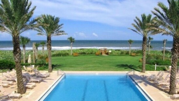 A pool with a view of the ocean, surrounded by palm trees and lounge chairs. - 4 King beds and En Suite Bathrooms - Ocean & Lake view, Elevator, 2 heated pools (Palm Coast)