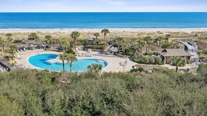 Ein Resort mit großem Schwimmbad, Zugang zum Strand und Palmen.