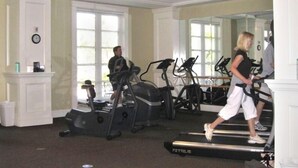 Un gimnasio con cintas de correr, elípticas y un espejo grande.