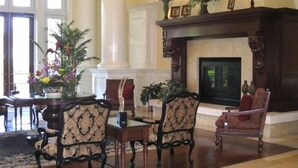 Un vestíbulo amplio con chimenea, elegantes sillas y un ventanal grande.