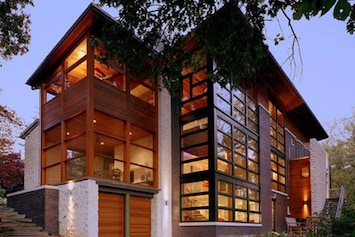 Wall of windows overlooking woods and a distant river view