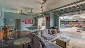 A spacious living area with a pool, a ping pong table, and a comfortable seating area.