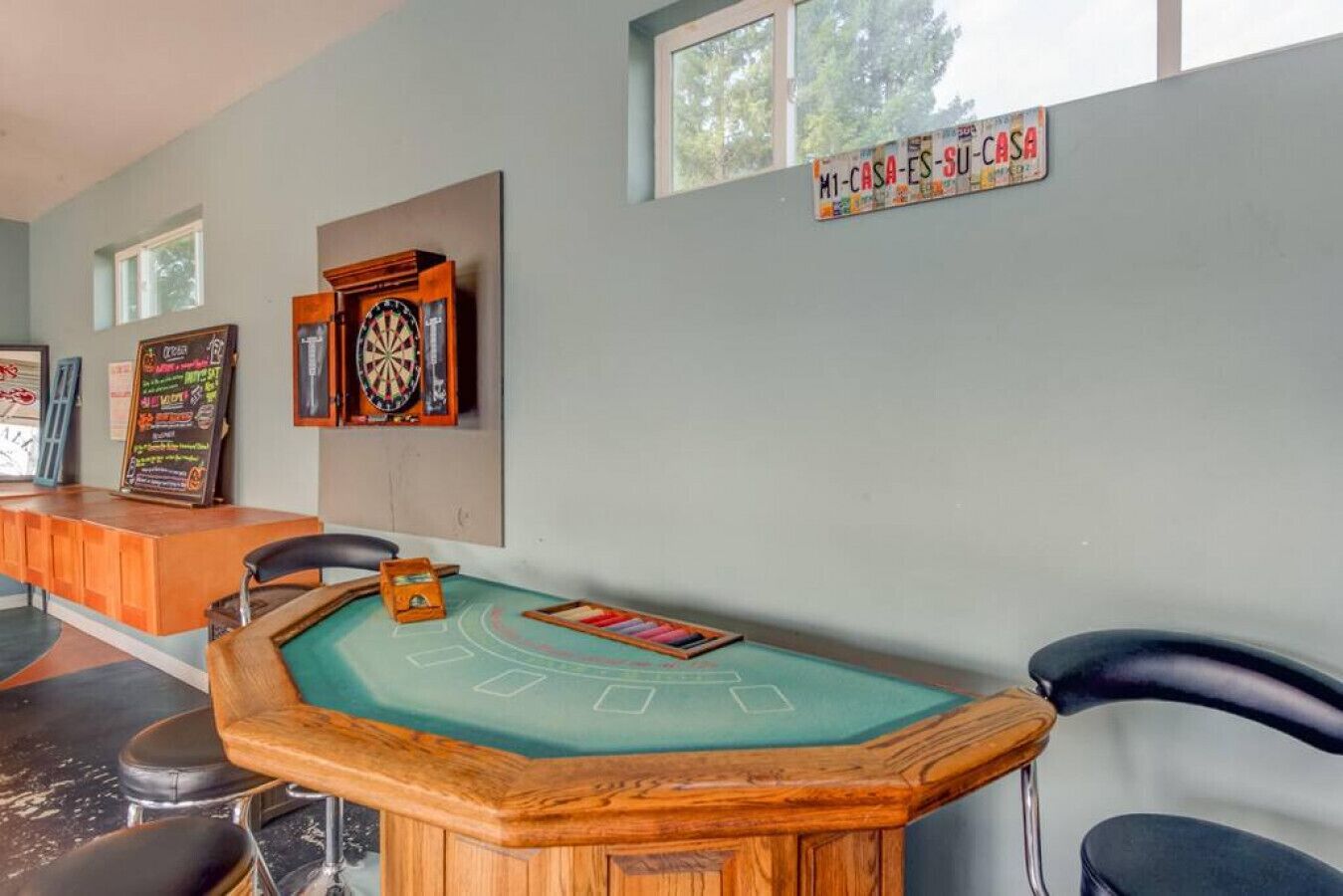 Um quarto com mesa de bilhar, dardos e um letreiro com a inscrição "M1-CASA-ES-SU-CASA".
